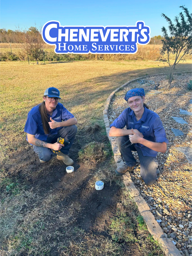 Two workers in blue uniforms kneel on the grass next to plumbing pipes, giving thumbs up, with a "Chenevert's Home Services" logo above them.